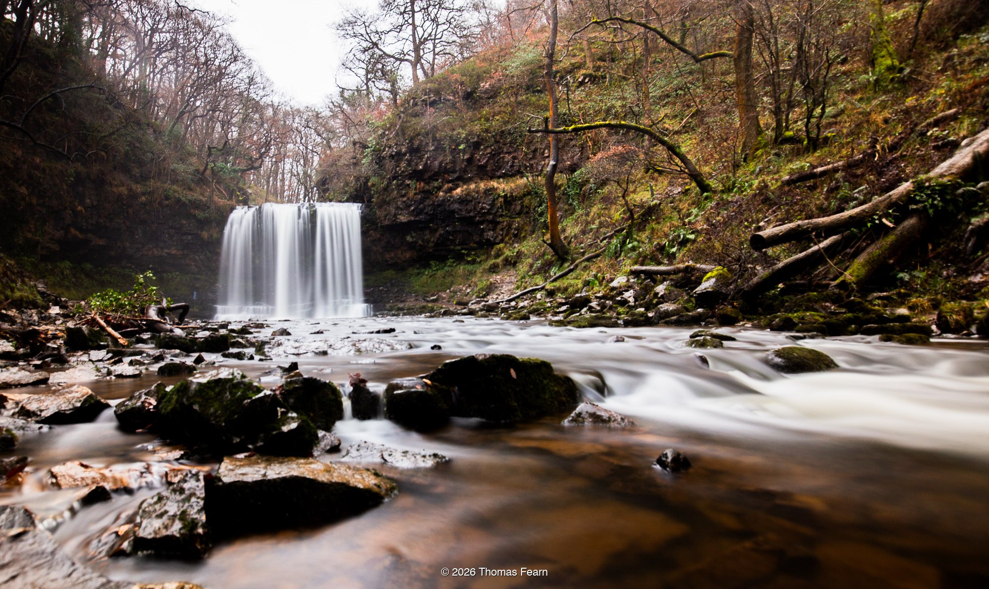 Waterfall stepping through autumn woodland